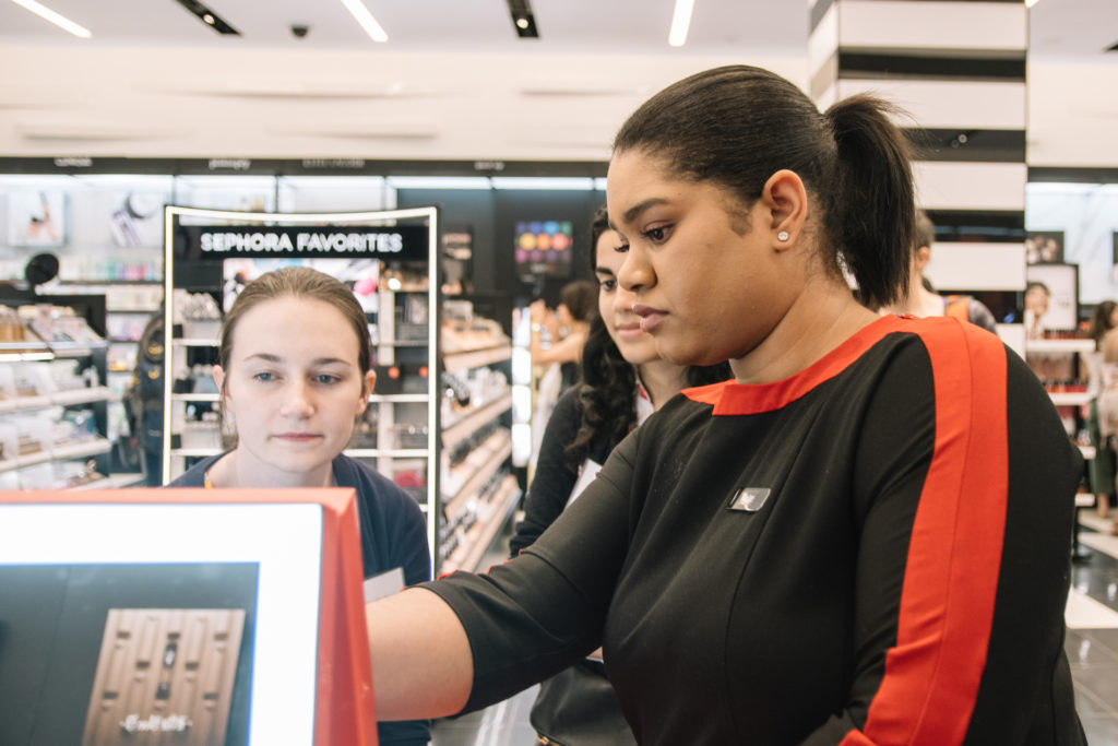 Sephora employee showing a customer how to use digital personalization kiosk