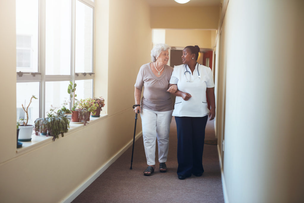 Senior woman walking with her nurse at nursing home