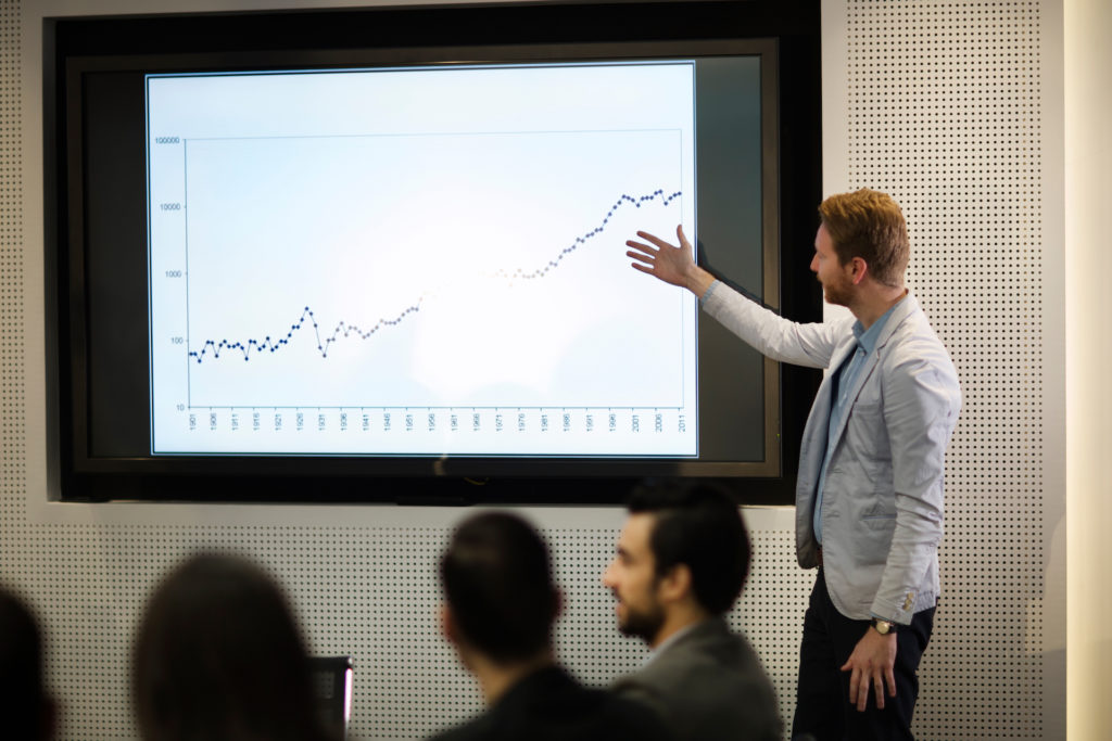 Young businessman showing data graph presentation to his colleagues in conference room