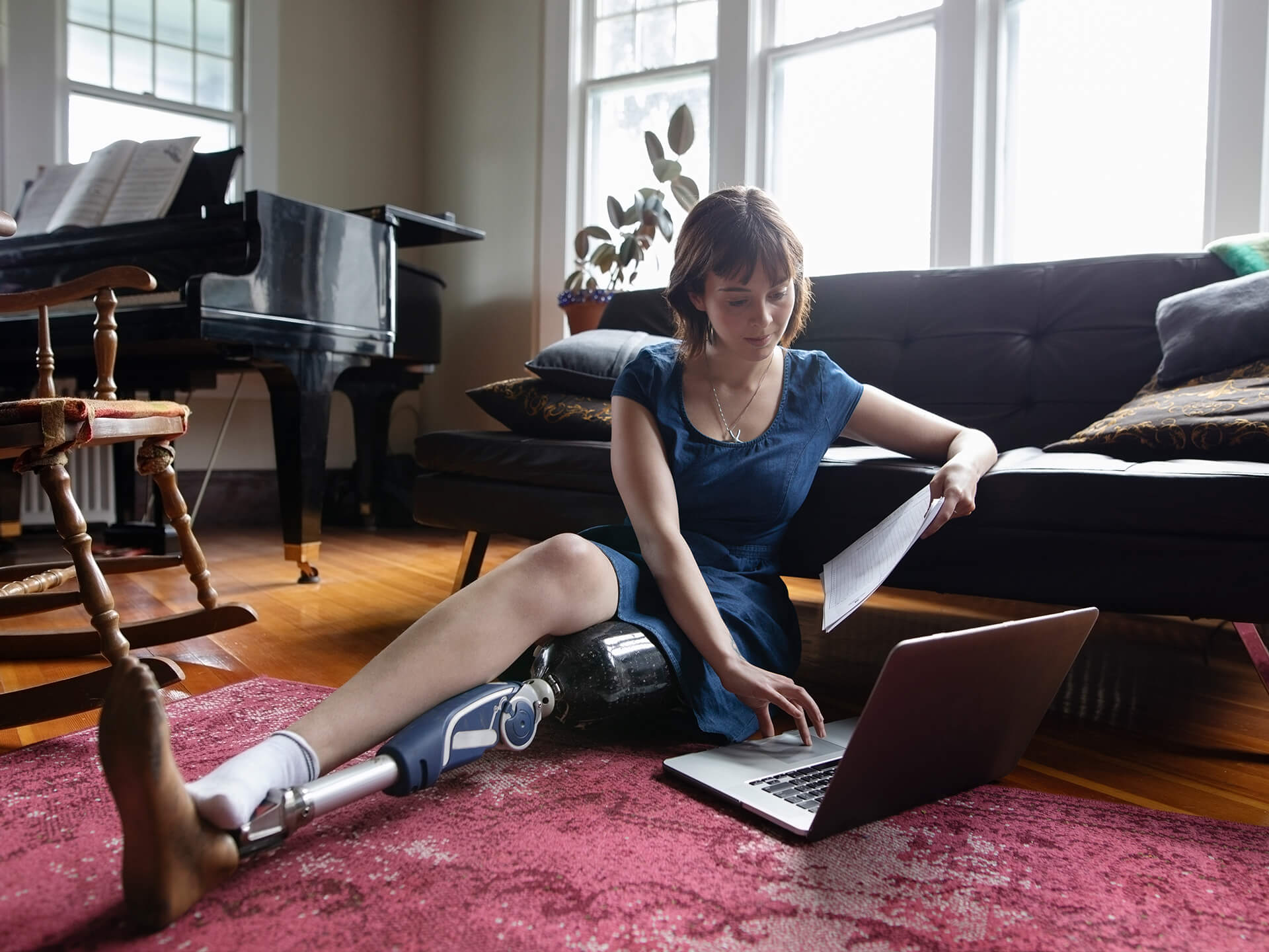 Woman sitting on floor looking at laptop.